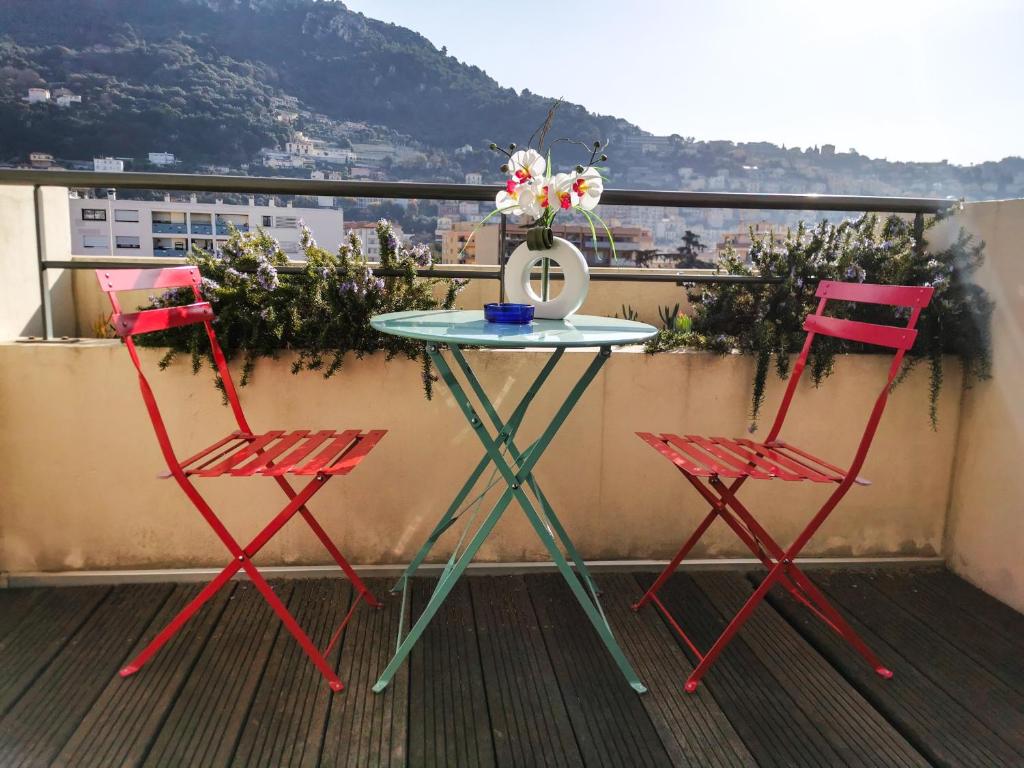 2 chaises et une table avec un vase de fleurs sur le balcon dans l'établissement Esatitude Hotel, à Nice