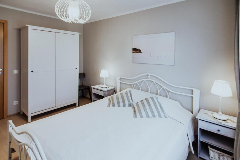 1 dormitorio con cama blanca y lámpara de araña en Lina apartamenti en Jūrkalne