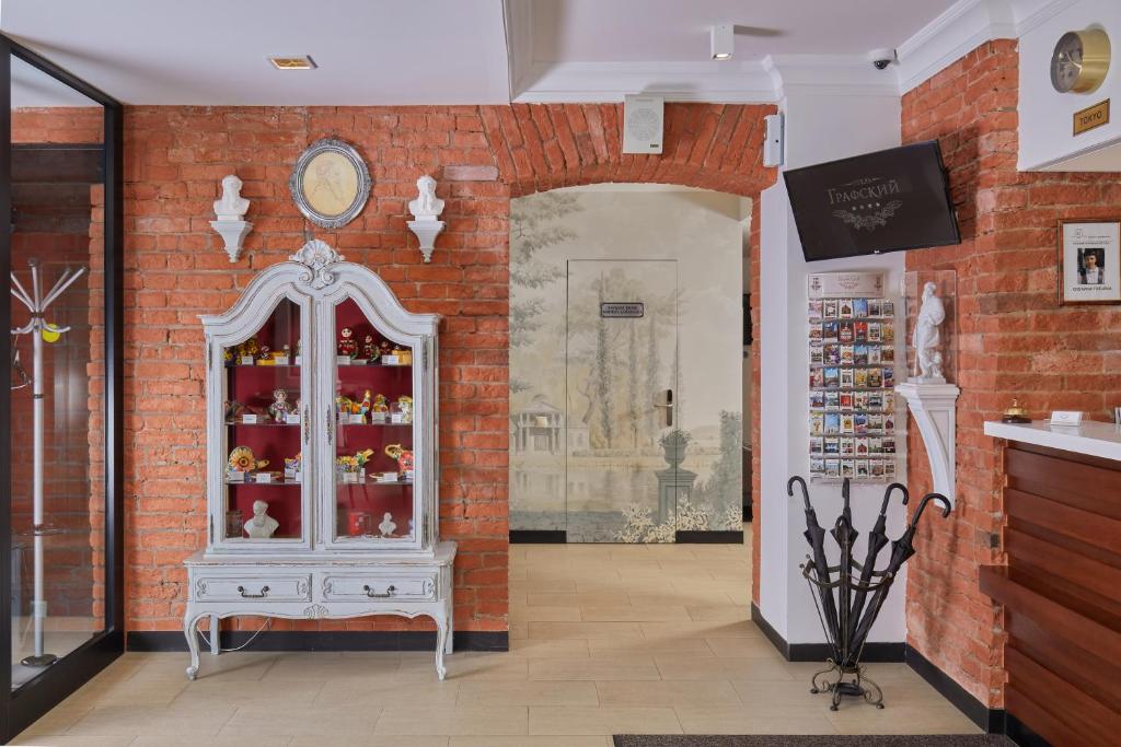 a room with a red brick wall and a display cabinet at Hotel Grafskiy in Moscow