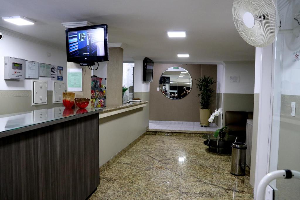uma sala de espera com uma televisão de ecrã plano e um espelho em Hotel Malka em São Paulo