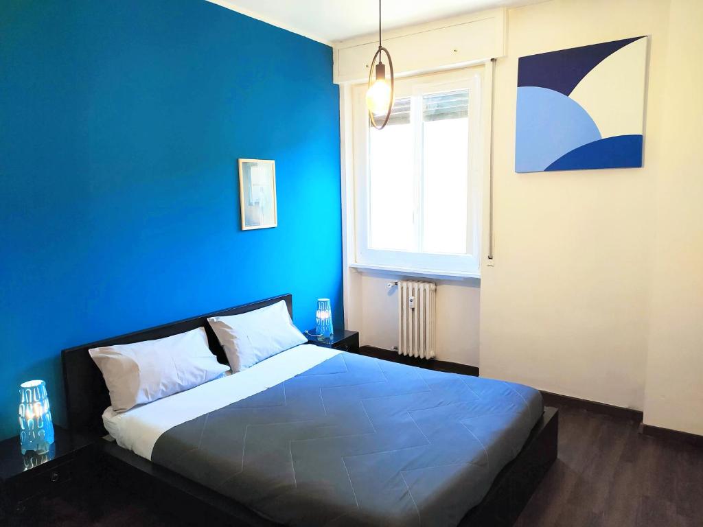 ein blaues Schlafzimmer mit einem Bett und einem Fenster in der Unterkunft Parsifal Apartment in Mailand