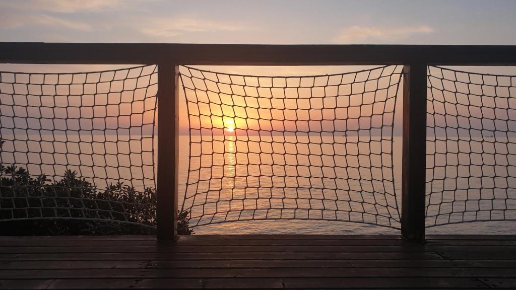 a sunset over the ocean through a volleyball net at Cala Dei Mori in Livorno