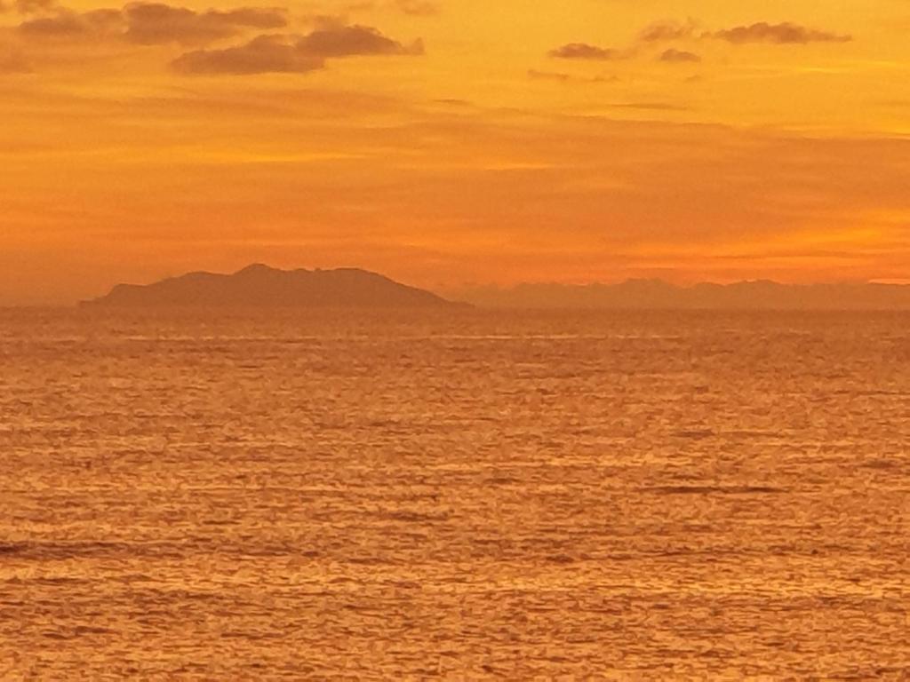 a sunset over the ocean with mountains in the background at Cala Dei Mori in Livorno