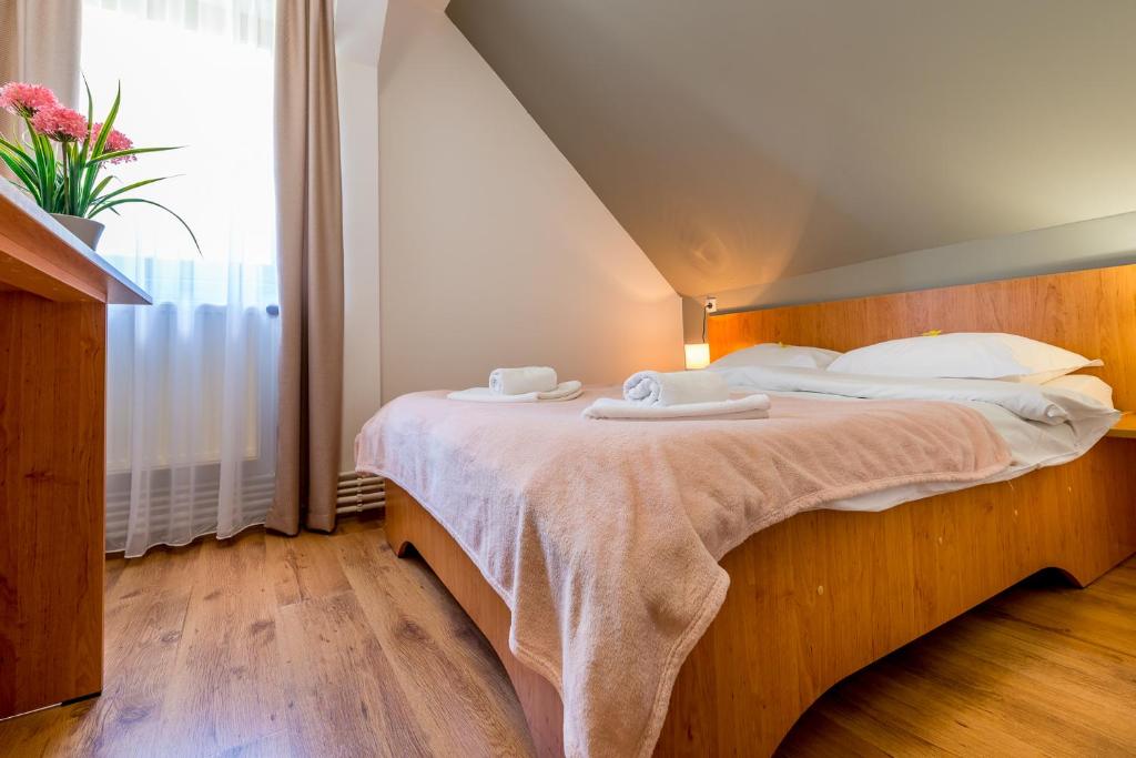 a bedroom with a large bed with two towels on it at Pensiunea Armonia in Nădăşelu