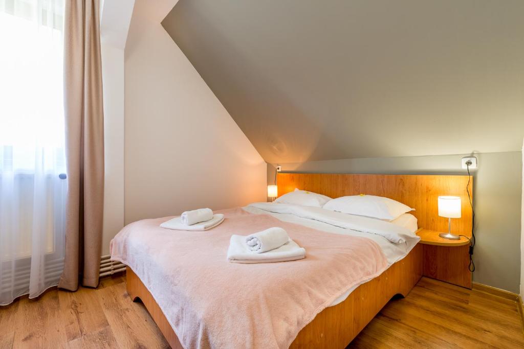 a bedroom with a large bed with towels on it at Pensiunea Armonia in Nădăşelu
