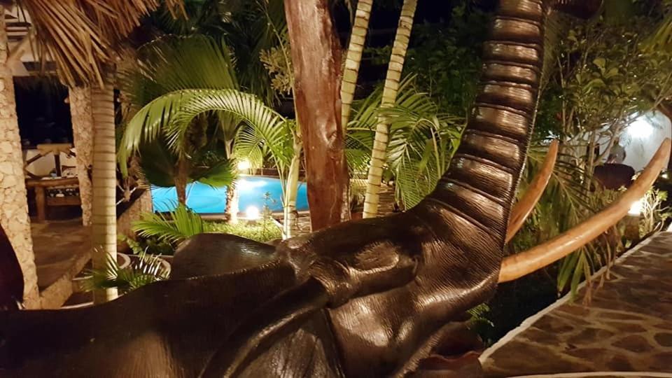Boutique Hotel Nyumbani Tembo في واتامو: تمثال لحيوان به أنياب أمام المسبح