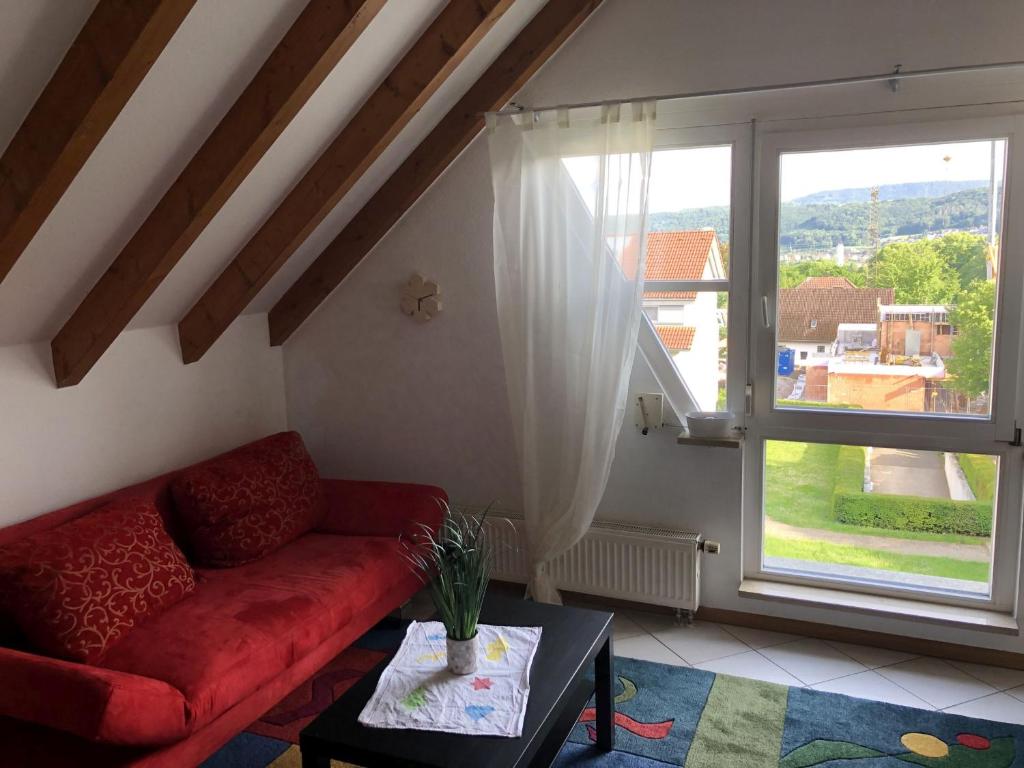 a living room with a red couch and a large window at Ferienwohnung Tetto Piccolo in Bad Säckingen