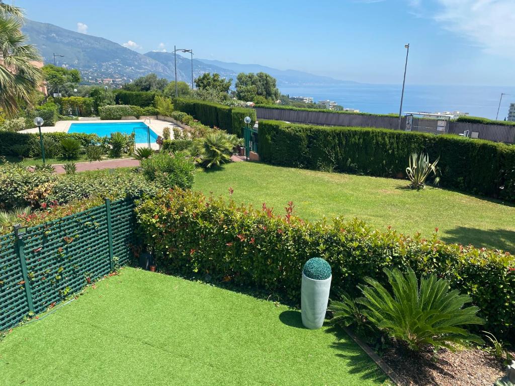 um jardim com uma cerca e uma piscina em Superbe 2P vue mer, ensoleillé, piscine em Roquebrune-Cap-Martin