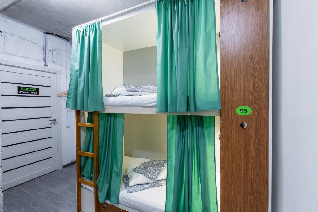 ソチにあるKapsulny Hostel MOLODOYの二段ベッド(緑色のカーテン付)が備わる客室です。