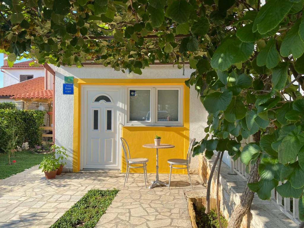 une petite maison jaune et blanche avec une table et des chaises dans l'établissement Anči, à Pula