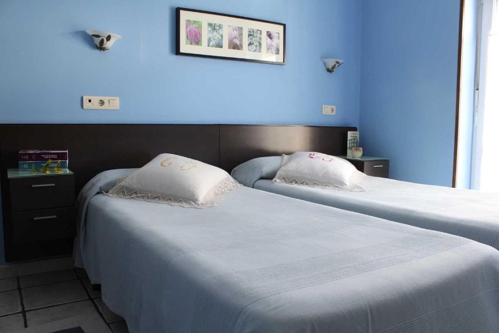 two beds in a hotel room with blue walls at Apartamentos Casa Germana in Tapia de Casariego