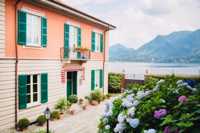 a house with green and white windows and flowers at Luxury Villa - Beach & Swimming Pool in Ghiffa