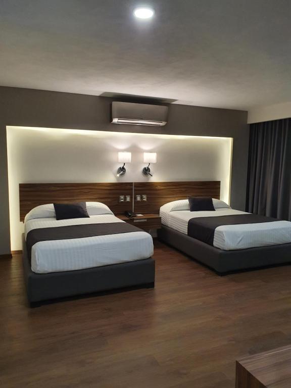 2 camas en una habitación de hotel con 2 camas sidx sidx sidx en Estanza Hotel & Suites en Morelia