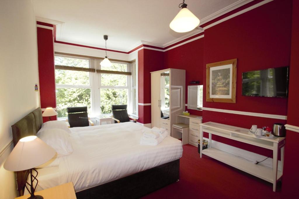 um quarto vermelho com uma cama branca e uma janela em The Dales em Harrogate