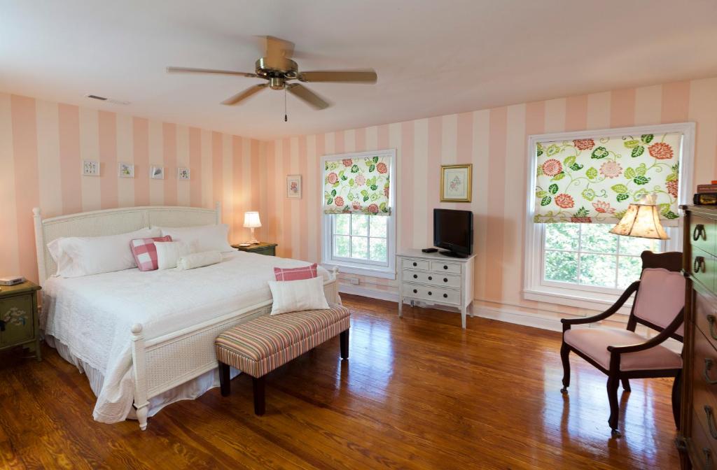 - une chambre avec un lit, une télévision et deux chaises dans l'établissement The Lily Inn - Burlington, à Burlington