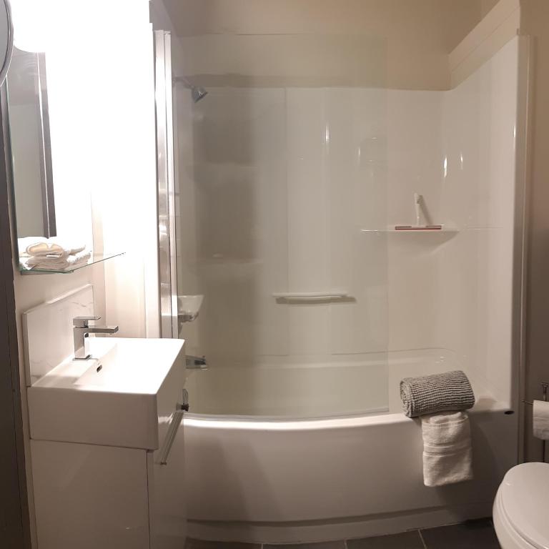 a white bathroom with a shower and a sink at Oberge Inn Val-David in Val-David