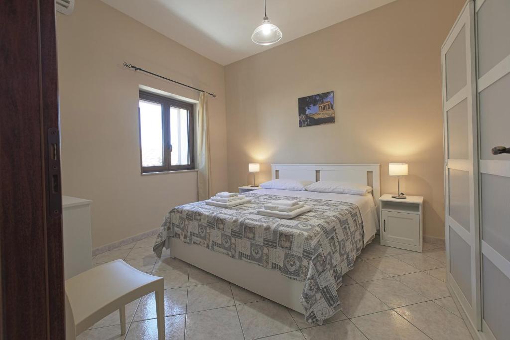 una camera con un letto e una sedia e una finestra di Zeus Atabyrios - Locazione Turistica a Agrigento