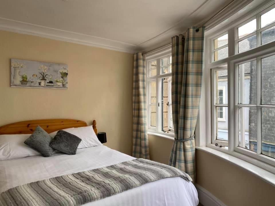 a bedroom with a bed and two windows at King William IV in Totnes
