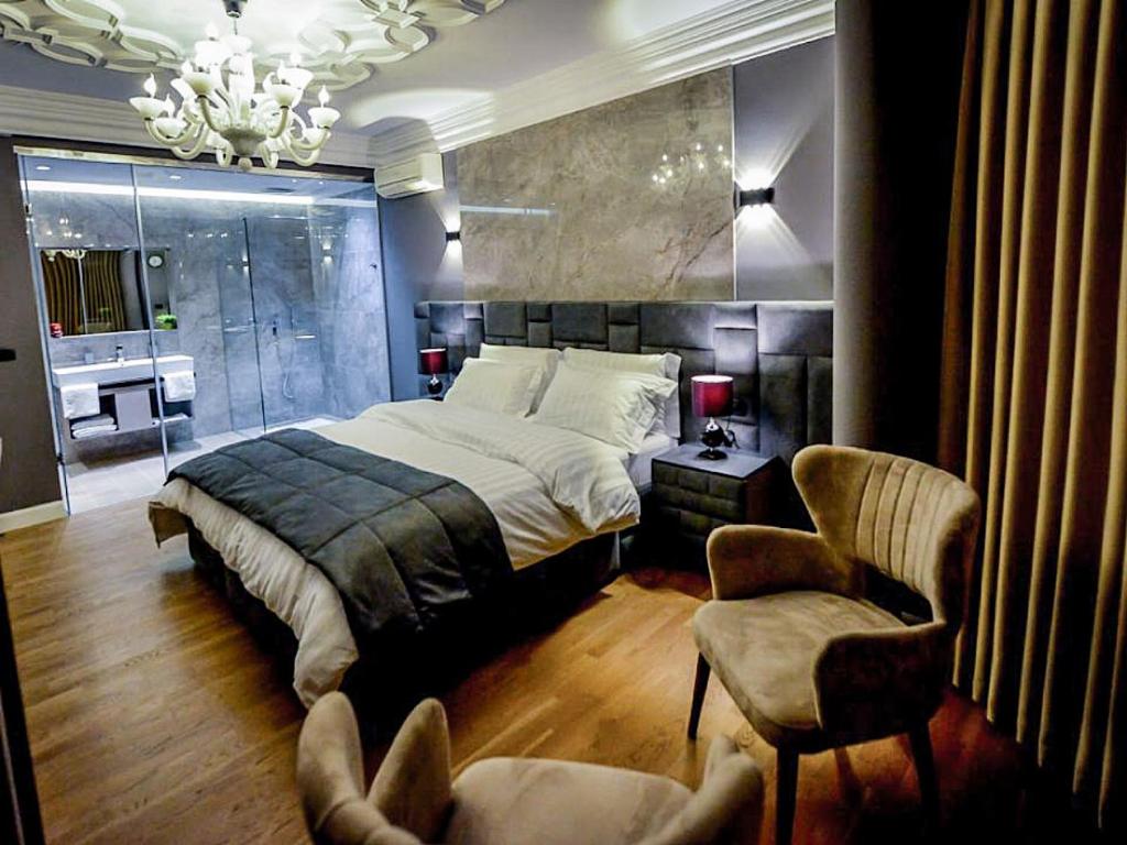 een slaapkamer met een groot bed en een stoel bij Hotel Vila Tirana in Tirana