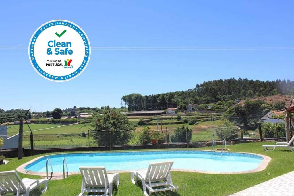 a swimming pool with chairs and a sign that says clean and safe at Vivenda Mendes in Outeiro