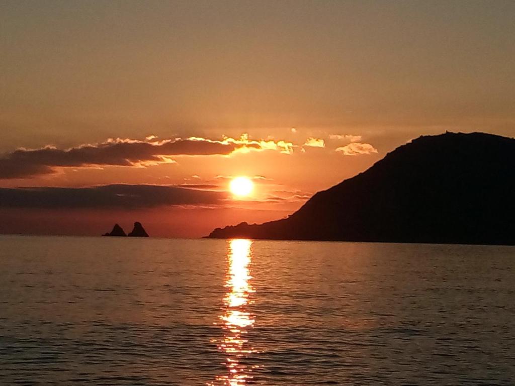 un coucher de soleil sur l'eau avec une montagne en arrière-plan dans l'établissement studio bord de mer, à Saint-Mandrier-sur-Mer