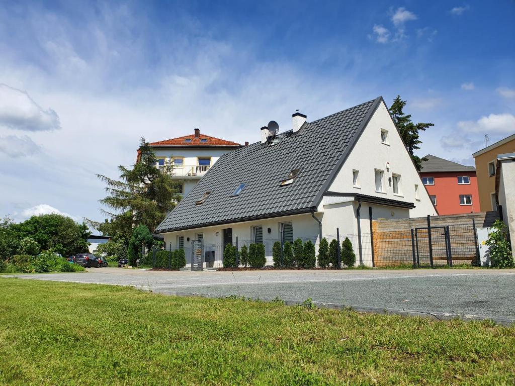 Biały dom z szarym dachem na ulicy w obiekcie 7apartments przy Termach Cieplickich w Jeleniej Górze