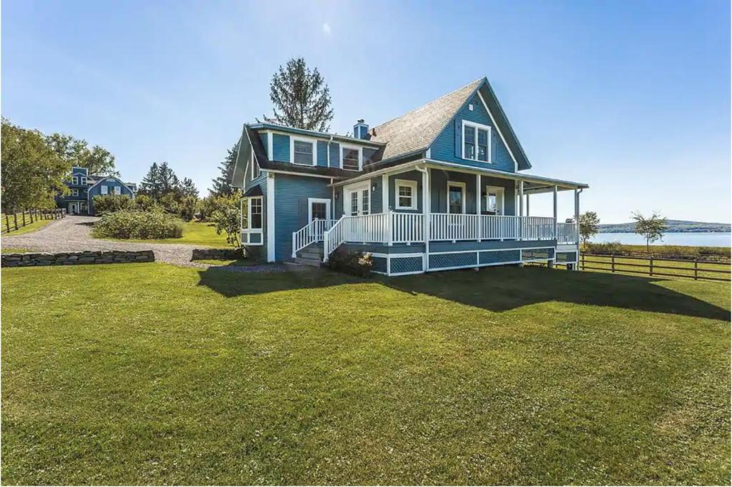 a blue house with a large yard at Lovely Lac-Brome 3 Bedroom Lakefront Cottage in Lac-Brome