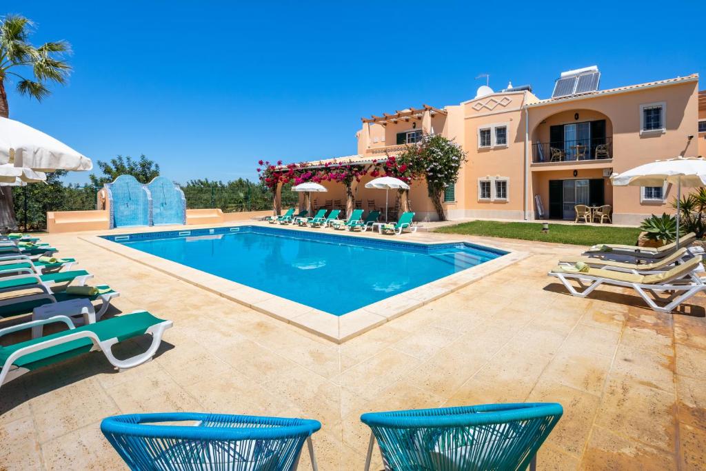 a villa with a swimming pool and patio furniture at Apartamentos Monte dos Avós, Albufeira in Albufeira