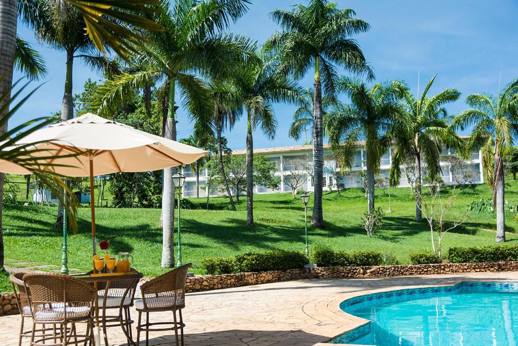 伊塔皮拉 米爾豪森的住宿－Hotel Fazenda Juca Mulato，游泳池旁的桌子、遮阳伞和椅子