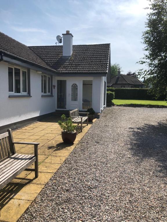 ein Haus mit zwei Bänken auf einer Kiesauffahrt in der Unterkunft Aslaich House in Drumnadrochit