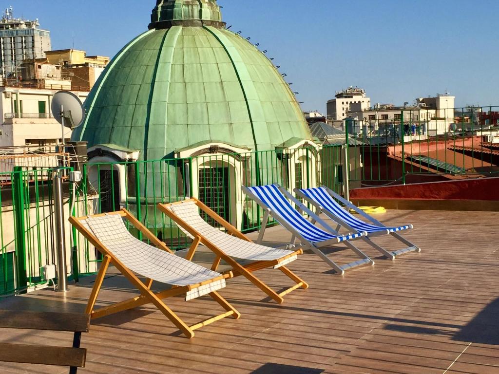 3 chaises longues sur un toit avec un bâtiment vert dans l'établissement Toledo Penthouse, à Naples