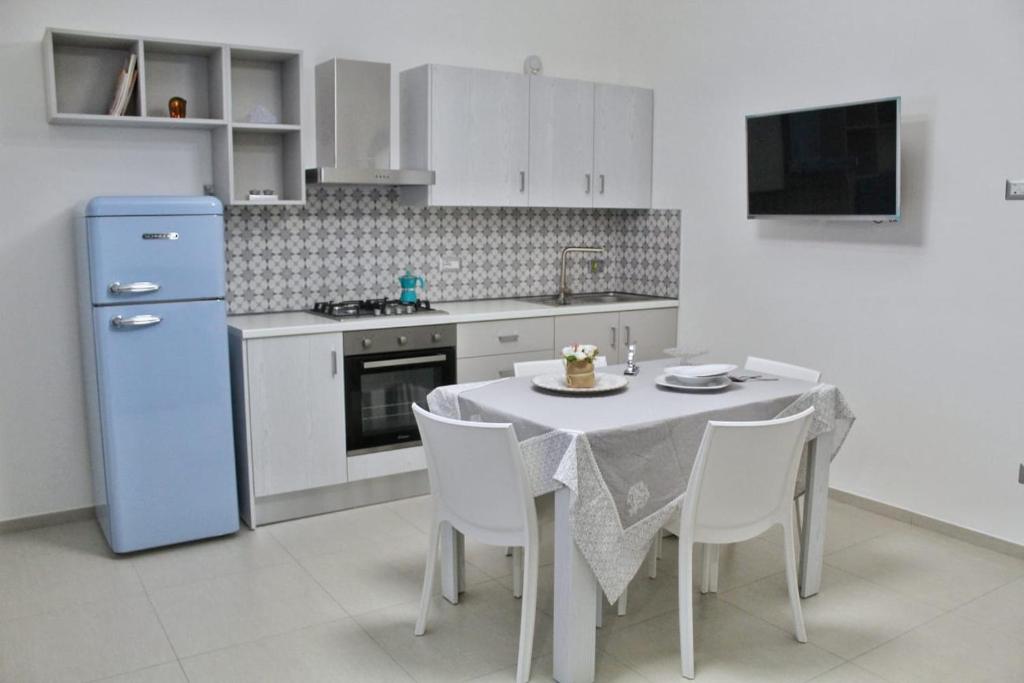 uma cozinha com uma mesa e um frigorífico azul em GIOANTHONY em Porto Cesareo