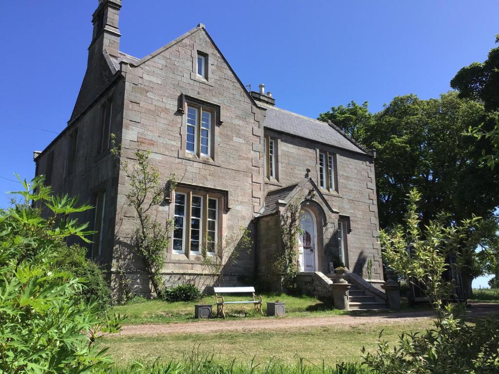 an old stone building with a bench in front of it at The Law House in Coldingham