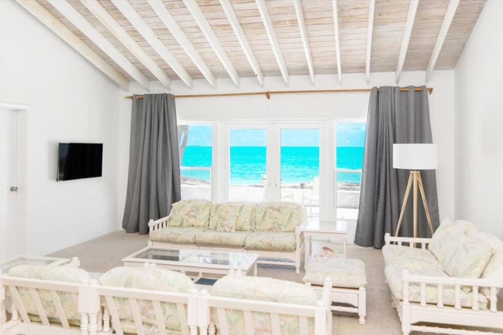 a living room with a couch and a view of the ocean at Beachfront White Palm Villa- Tar Bay, Great Exuma in Rokers Point Settlement