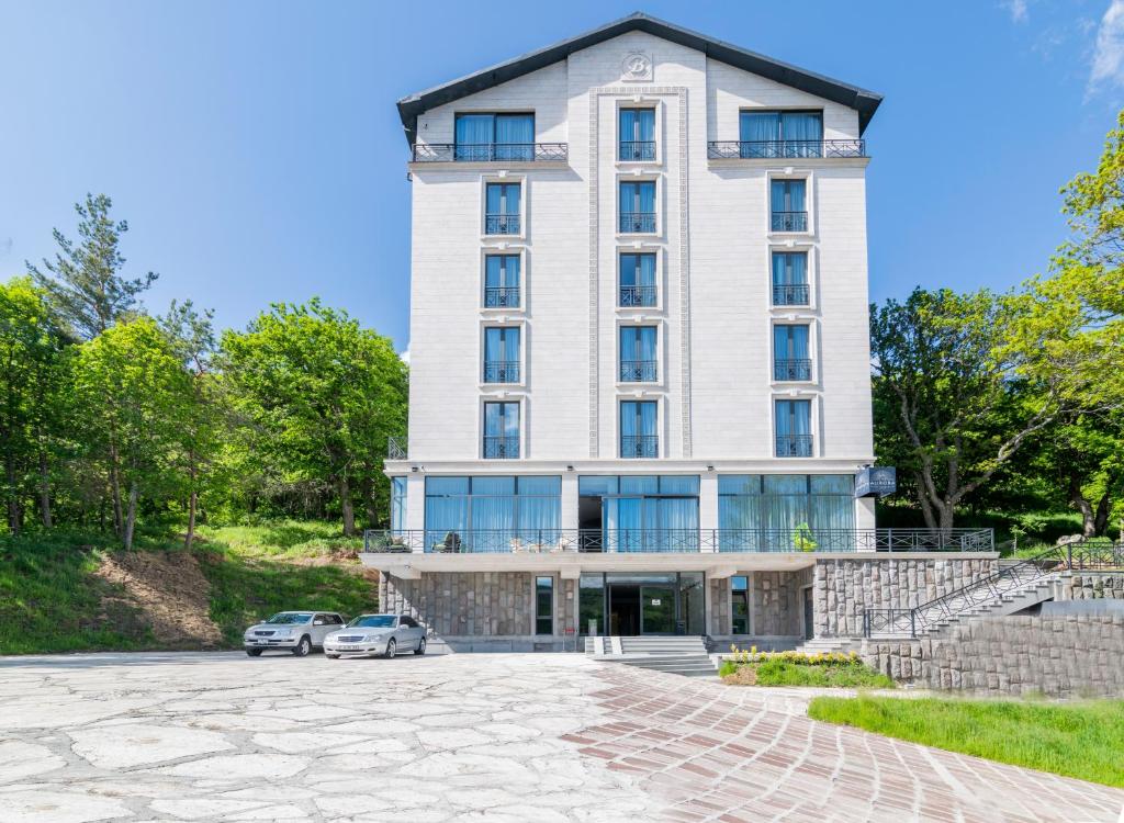 un edificio con dos coches estacionados frente a él en Aurora Resort by Stellar Hotels, Tsaghkadzor, en Tsaghkadzor