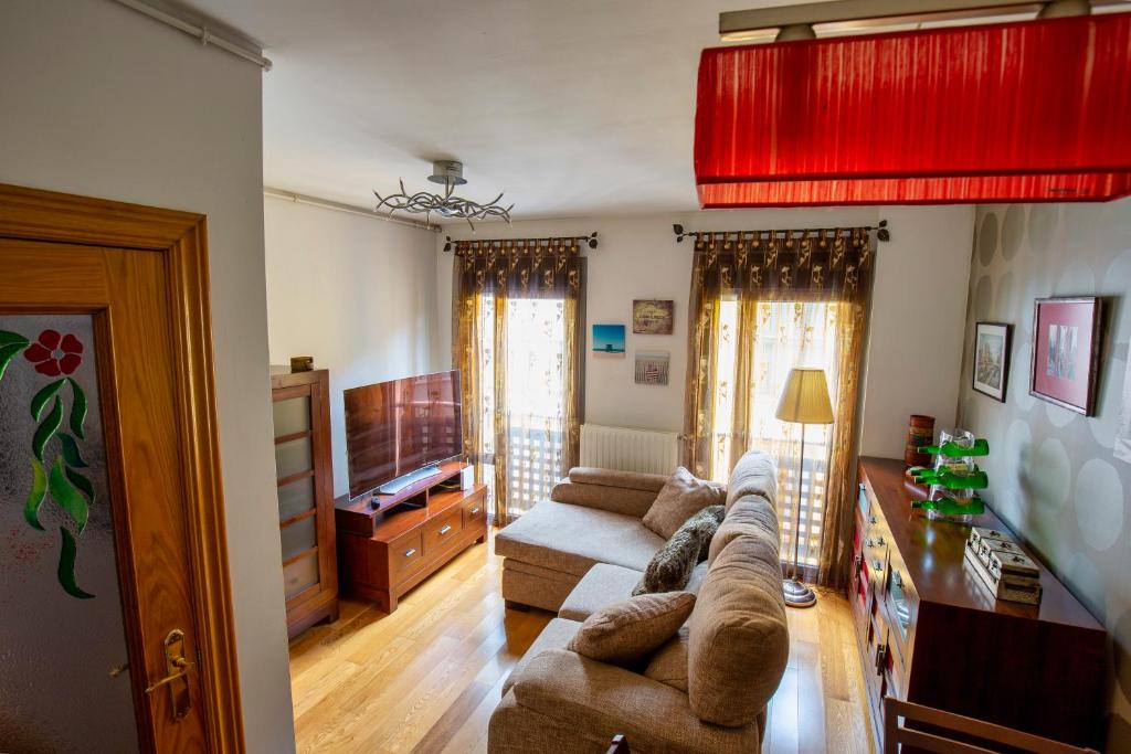 uma sala de estar com um sofá e uma televisão em Duplex con encanto en Cimadevilla em Gijón