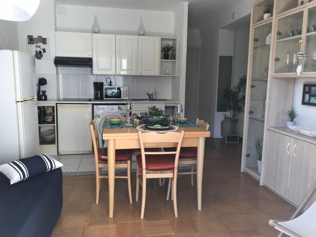 une cuisine avec une table et des chaises et une cuisine avec des armoires blanches dans l'établissement Charmant appartement au cœur de Juan les Pins, à Antibes
