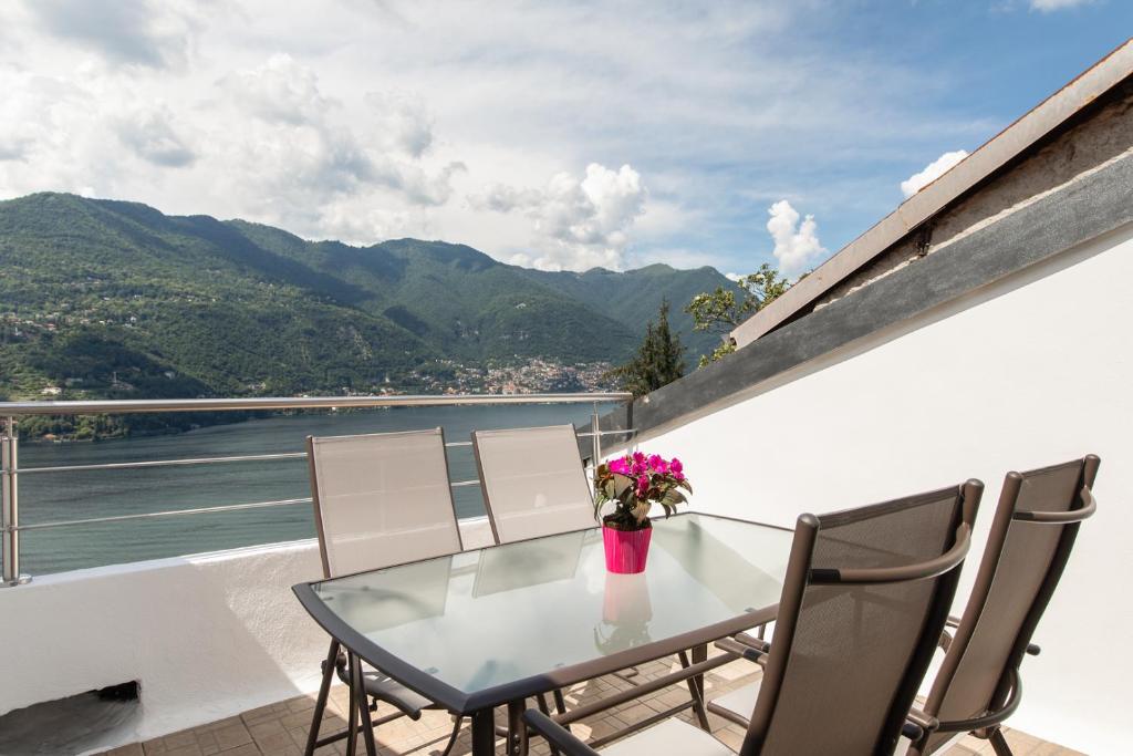 d'une table en verre avec des chaises et des fleurs sur le balcon. dans l'établissement La Terrazza sul Lago di Como con garage, à Blevio