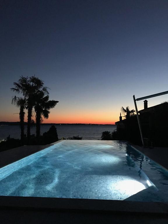 a swimming pool with a view of the ocean at sunset at Portorož Apartments in Portorož