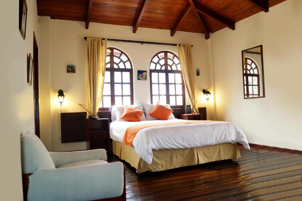 a bedroom with a large bed and two windows at Kitu Hotel in Quito