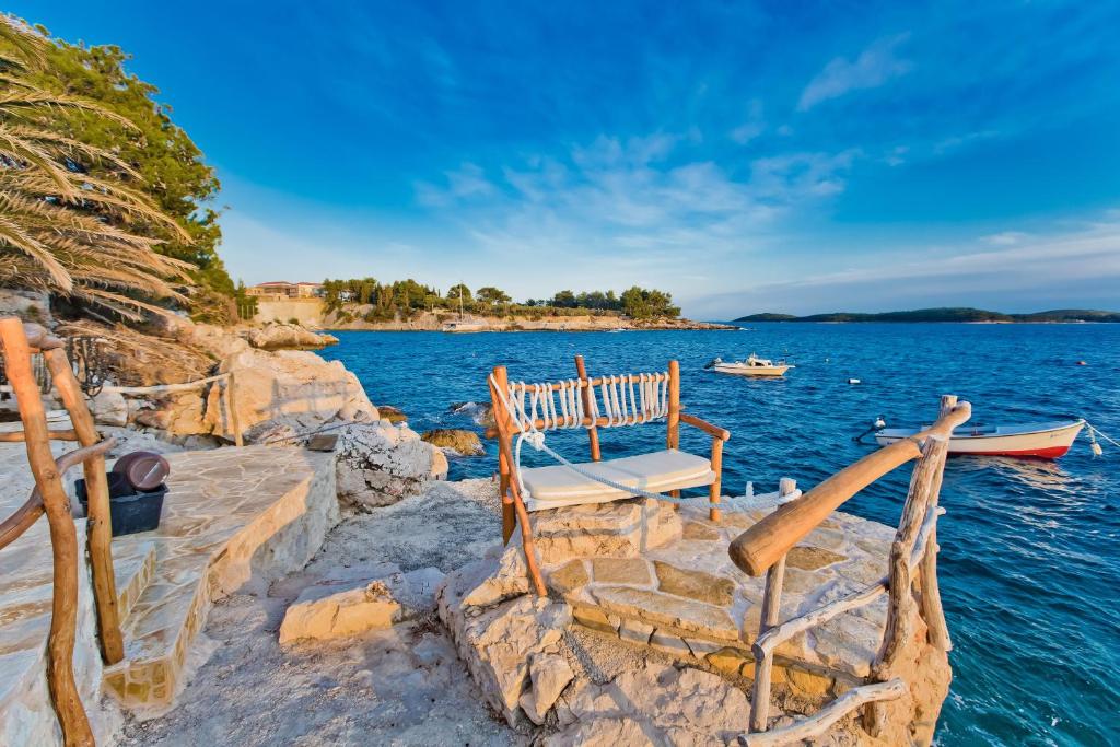 a bench sitting on the side of a body of water at Apartments Villa Marcelina in Hvar