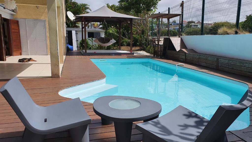 una piscina con una silla y un taburete junto a ella en Villa Mango en Le Gosier