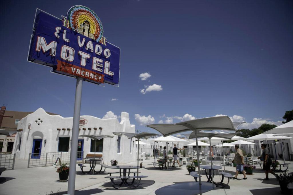 un cartel frente a un motel con mesas y sombrillas en El Vado Motel en Albuquerque