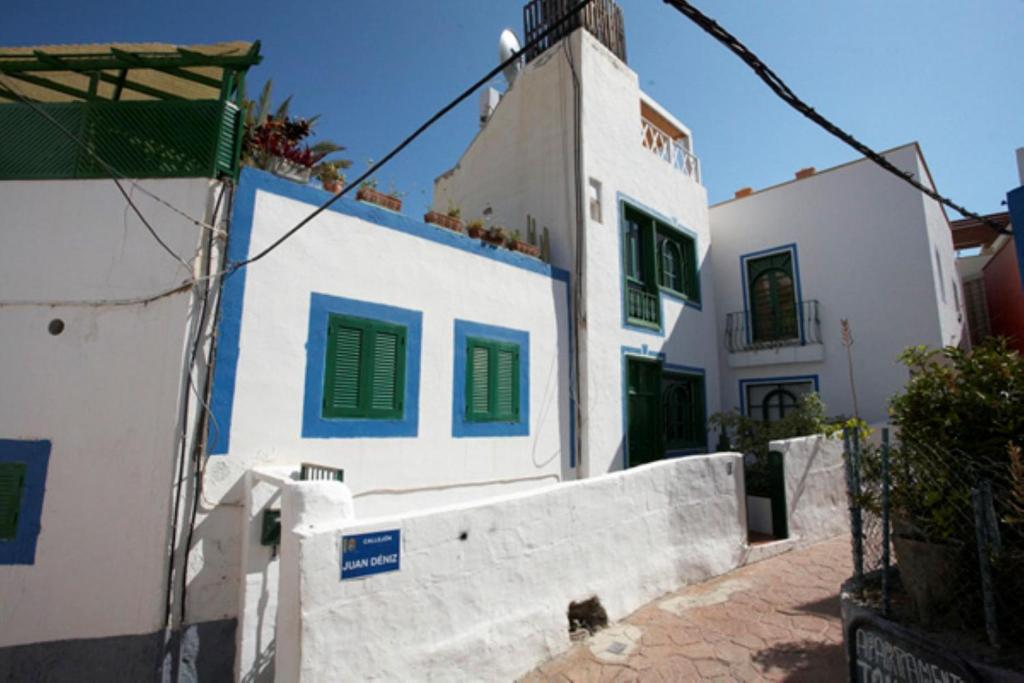 a white building with green shutters on it at Captains House Playa De Mogan in Puerto de Mogán