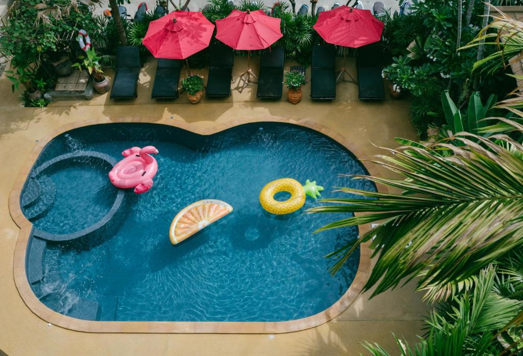 una pequeña piscina con sombrillas y un flamenco de juguete en The Odyssey Chiang Mai, en Chiang Mai