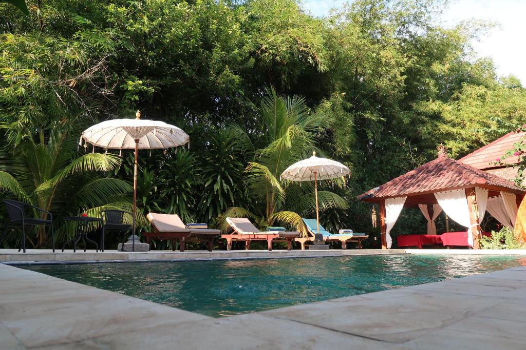 特賈庫拉的住宿－Villa Aditya，游泳池旁设有椅子和遮阳伞