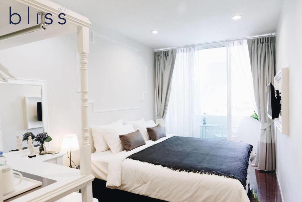 a white bedroom with a bed and a large window at Bliss Silom Bangkok in Bangkok