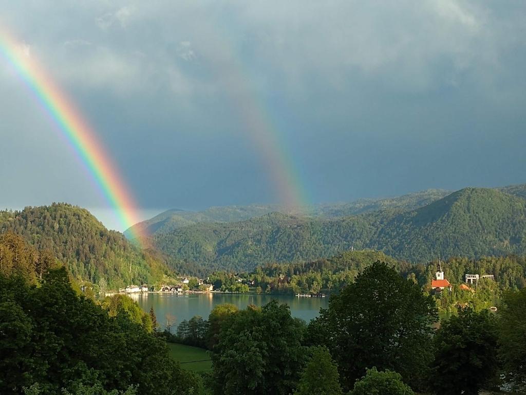 a rainbow over a lake with trees and mountains at Island View Apartment in Bled
