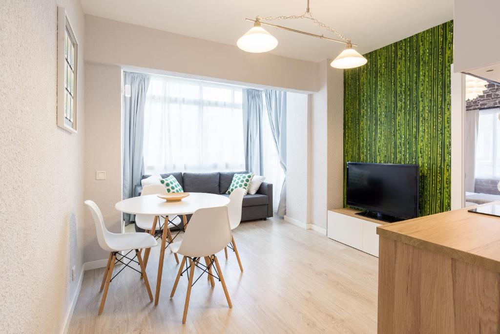 een woonkamer met een tafel en stoelen en een televisie bij Málaga Beach and Historic centre Malagueta in Málaga