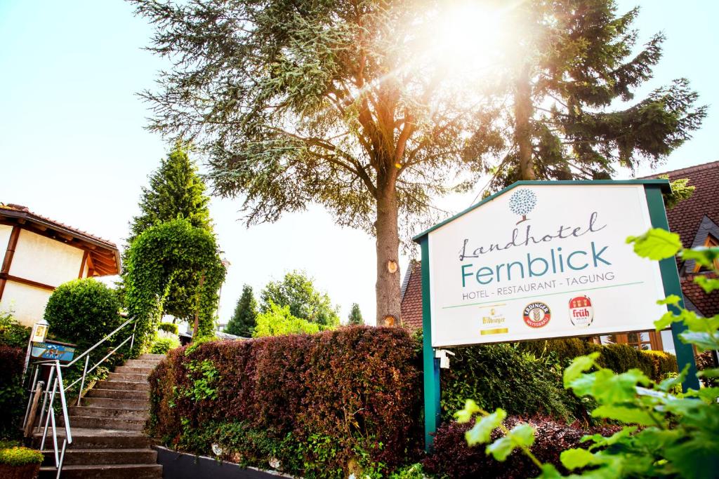 a sign in front of a building with a tree at Landhotel Fernblick in Hümmerich